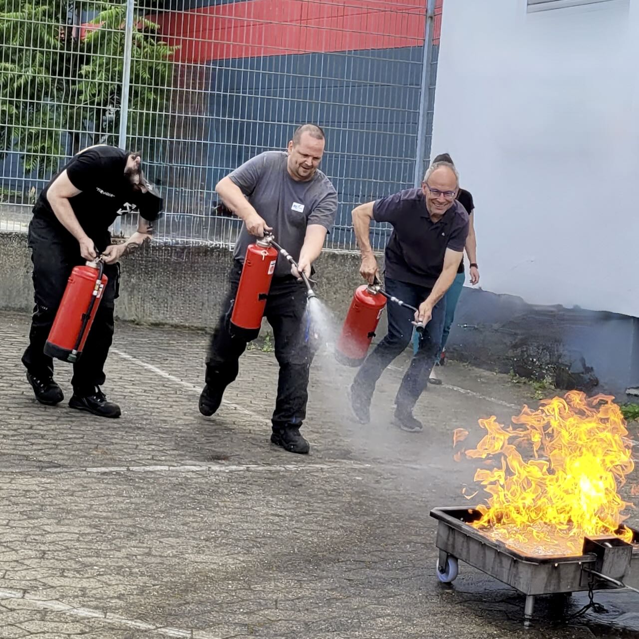 Drei Männer erfüllen die Brandschutzhelfer Aufgabe zu löschen. Bildkorrektur nachträglich durchgeführt.