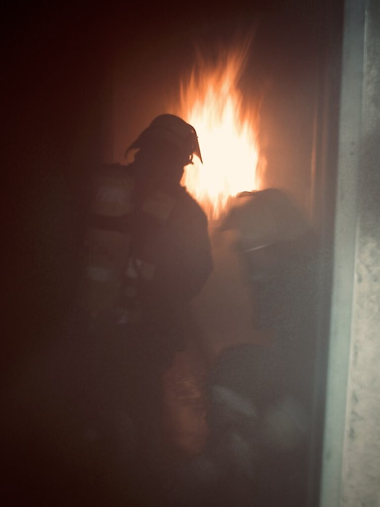 Berufsfeuerwehrmänner trainieren an einer echten Brandstelle unter realen Einsatzbedingungen für die Brandschutzhelfer Auffrischung.