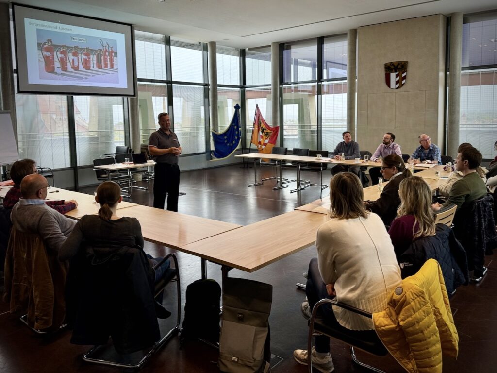 Theoretischer Unterricht während einer Brandschutzhelfer Ausbildung in Bayern mit aktivem Berufsfeuerwehrmann und Teilnehmenden im Seminarraum der Gemeinde.
