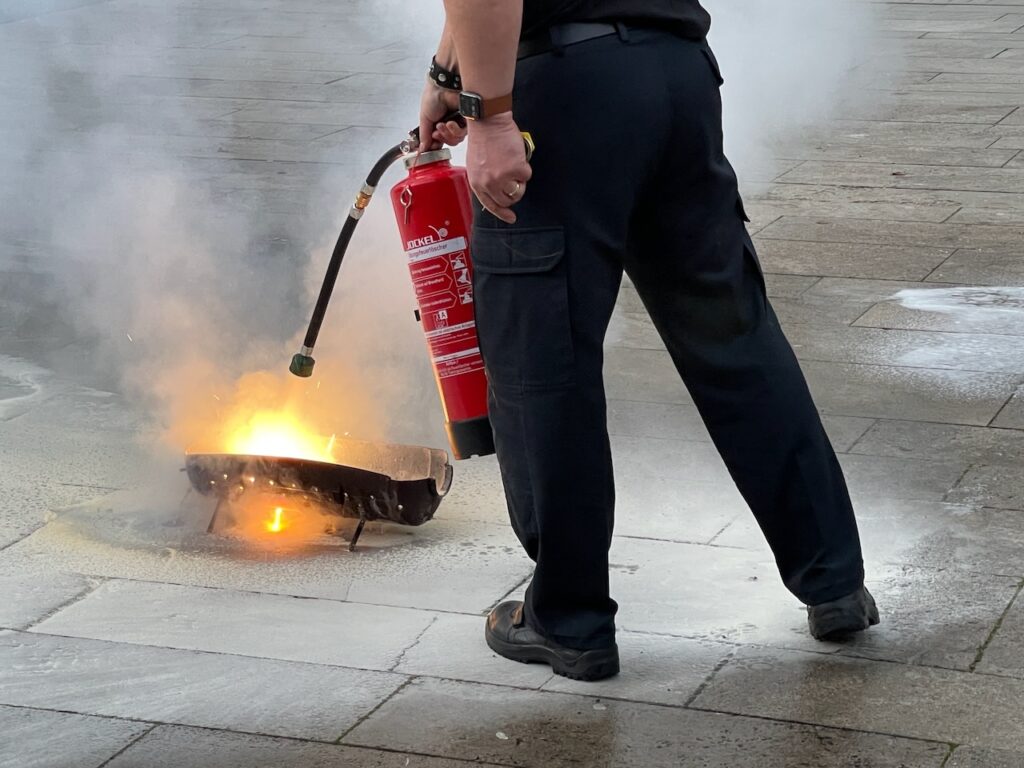Praktisches Brandschutztraining: Teilnehmender löscht einen realen Übungsbrand mit einem Feuerlöscher