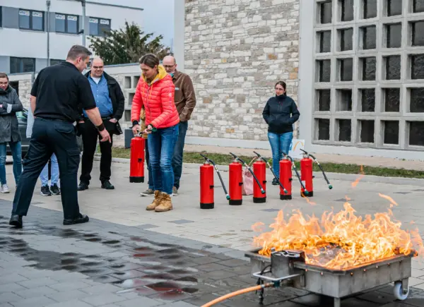 Teilnehmende üben den Umgang mit Feuerlöschern bei einem Brandschutzhelfer Kurs im Betrieb