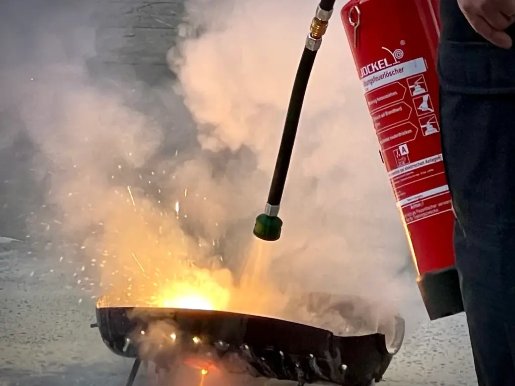 Teilnehmende üben den Umgang mit Feuerlöschern bei einer Brandschutzhelfer Schulung in Baden-Württemberg