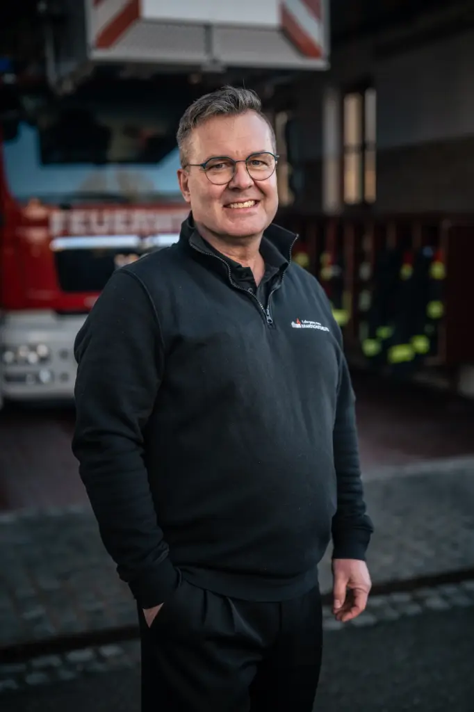 Thomas Till, Oberbrandmeister der Berufsfeuerwehr, Ausbilder für Brandschutzhelfer mit Einsatz- und Leitstellenpraxis vor einer Drehleiter