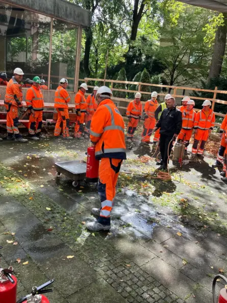 Berufsfeuerwehrmann Thomas Till führt eine praktische Löschübung mit Mitarbeitern der Firma ZECH Bau während einer Brandschutzhelfer-Ausbildung auf einer Baustelle in München durch.