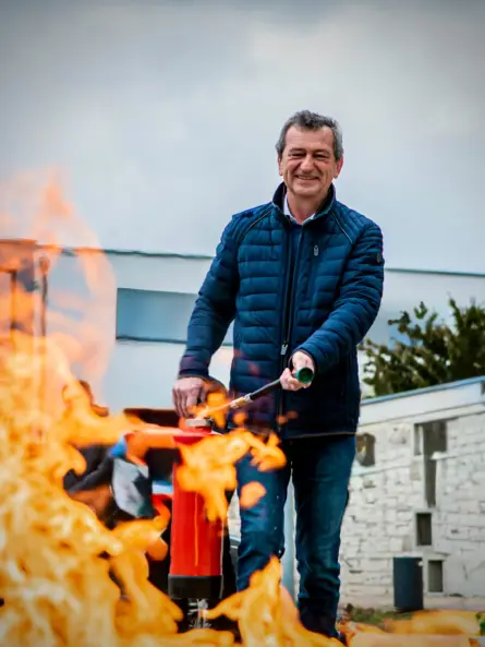 Teilnehmer einer Brandschutzhelfer-Ausbildung setzt einen Feuerlöscher selbstsicher beim Umgang mit Feuerlöschern ein.