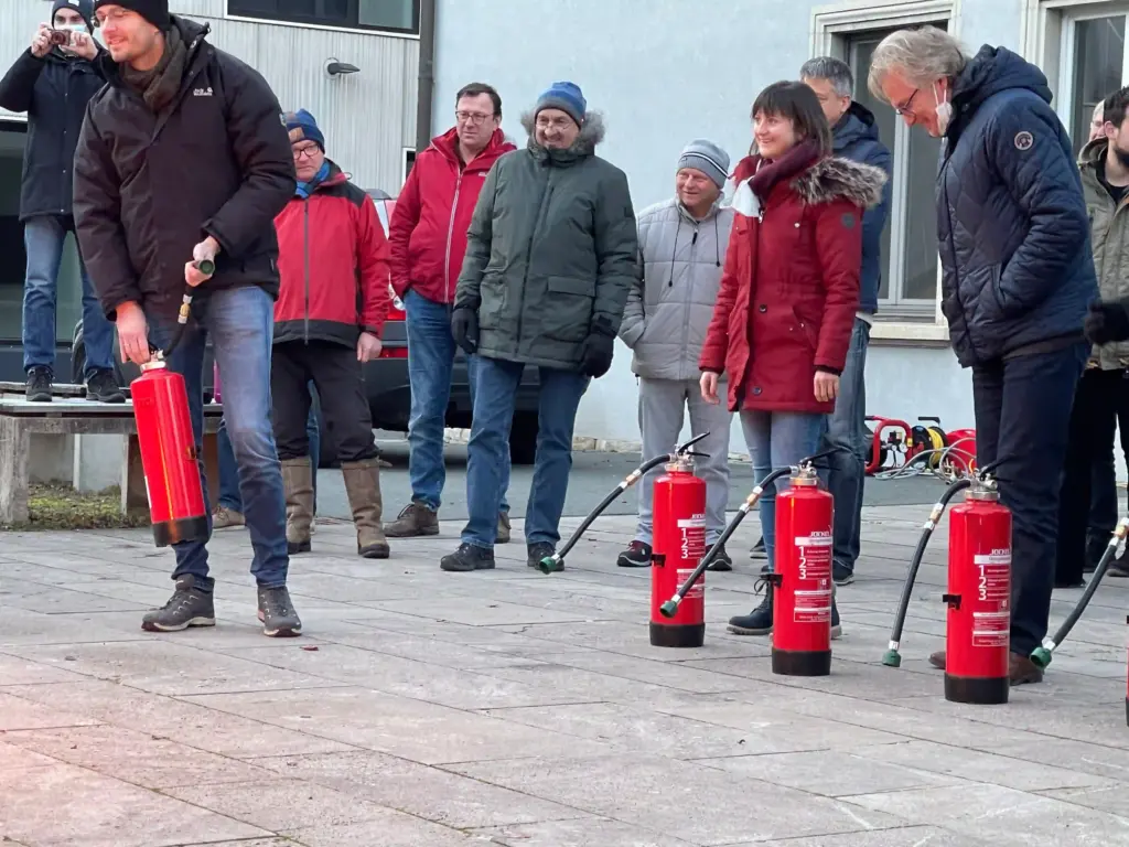 Teilnehmer einer Brandschutzhelfer-Ausbildung übernimmt bei einer praktischen Löschübung die Verantwortung für einen Löschversuch mit einem Feuerlöscher.