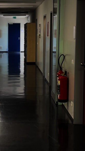Umgang mit Feuerlöschern im Unternehmen: Zwei Feuerlöscher hängen nebeneinander in einem Betriebsgebäude und stehen für einen möglichen gleichzeitigen Löscheinsatz zur Verfügung.