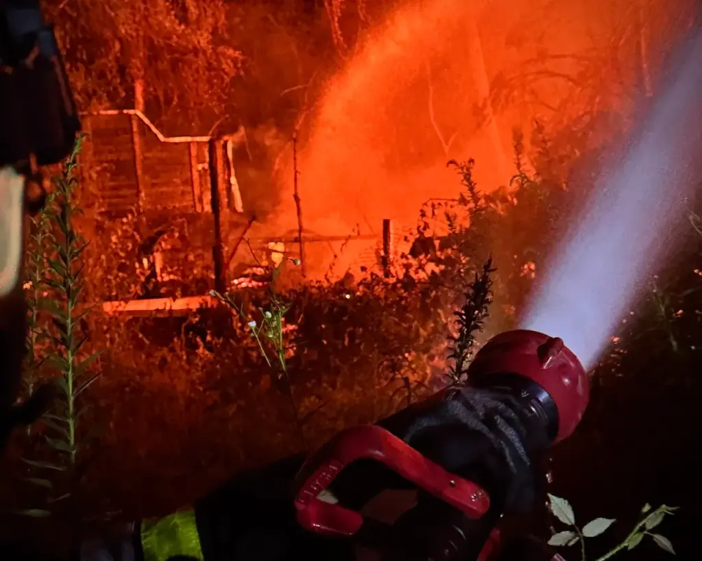 Feuerwehrmann bekämpft mit einem Strahlrohr einen Brand, der nicht mehr mit einem Feuerlöscher beherrscht werden kann.