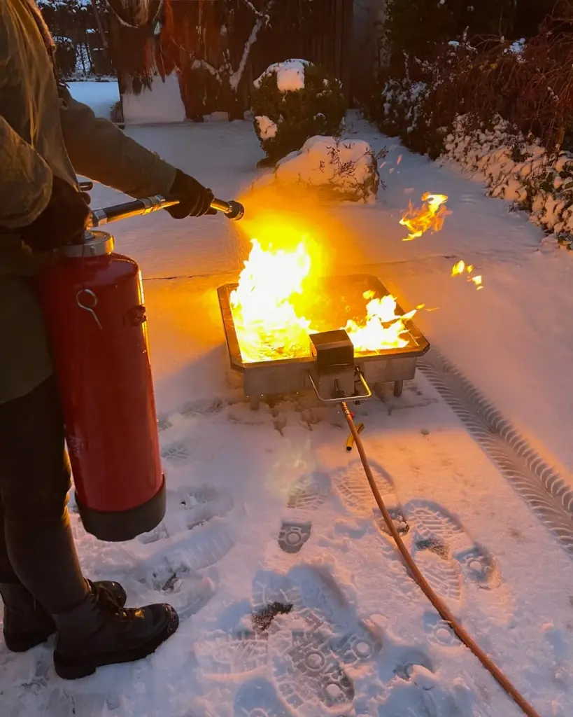 Praktische Löschübung im Winter bei einem Brandschutzhelfer-Kurs mit Feuerlöscher am Brandsimulator