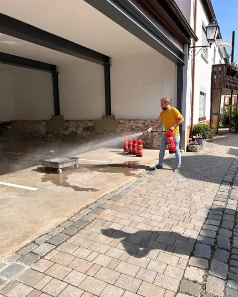 Praktische Löschübung eines Brandschutzhelfer-Kurses auf einem Garagenvorplatz