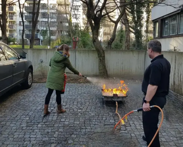 Praktische Löschübung auf einer kleinen befestigten Übungsfläche neben einem Firmengebäude