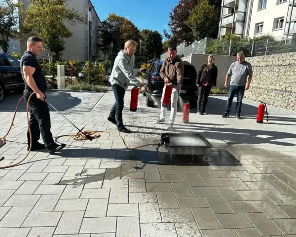 Praktische Löschübung eines Brandschutzhelfer-Kurses auf einer etwa zwei PKW-Stellplätze großen Übungsfläche