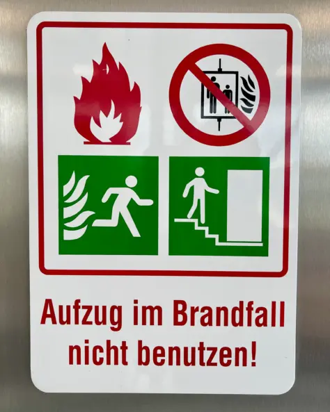 Brandschutzhelfer Aufgaben: Sicherheitskennzeichnung „Aufzug im Brandfall nicht benutzen“ weist auf sichere Fluchtwege hin