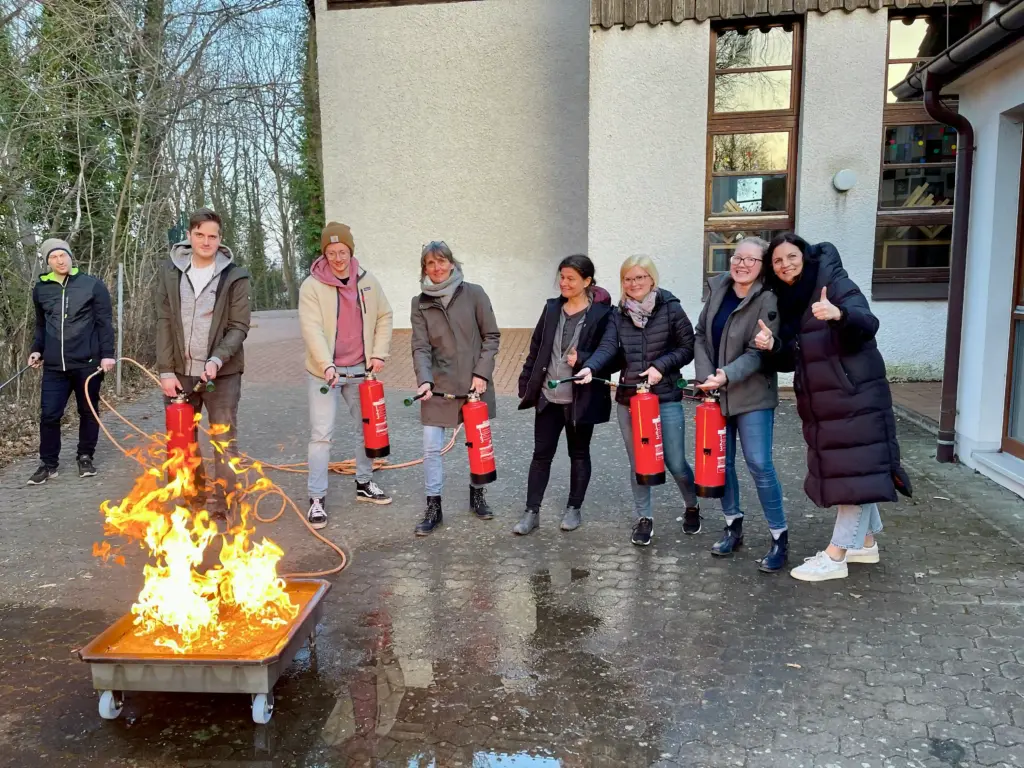 Teilnehmende einer Brandschutzhelfer-Ausbildung bei einer praktischen Löschübung mit