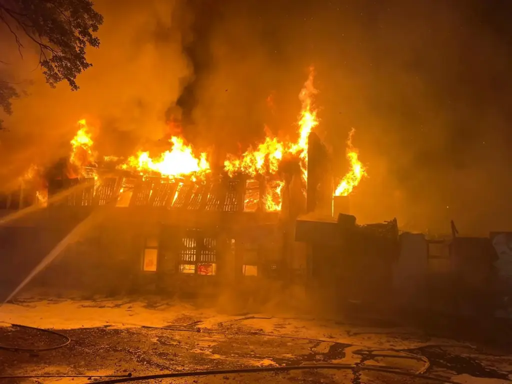 Weit entwickelter Gebäudebrand bei Nacht mit großen Flammen im Dachbereich während eines Feuerwehreinsatzes