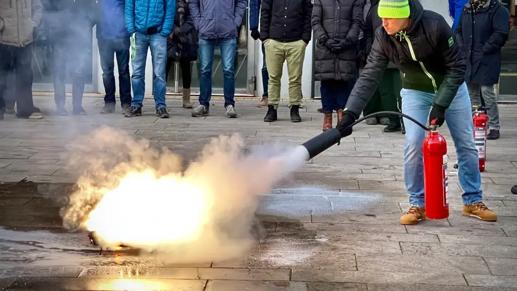 Teilnehmer bei einer Brandschutzhelfer-Schulung in Stuttgart während einer praktischen Löschübung mit Feuerlöscher.